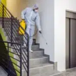 adetto in tuta bianca sanificazione scale di condominio